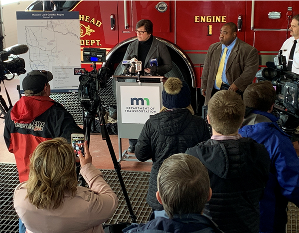 Commissioner Anderson Kelliher speaking to reporters at news conference with Moorhead mayor and fire chief at her side.